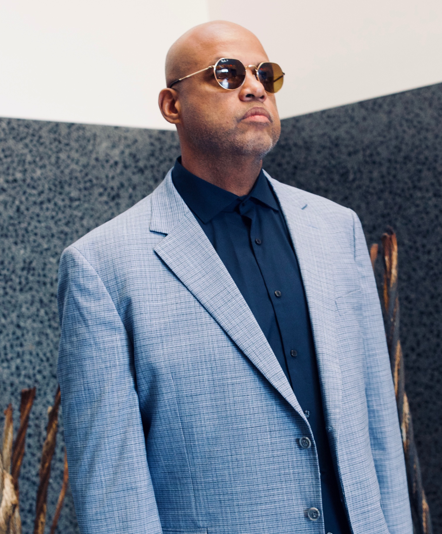 Portrait of Byron Jupiter in a light-blue jacket and tinted glasses.