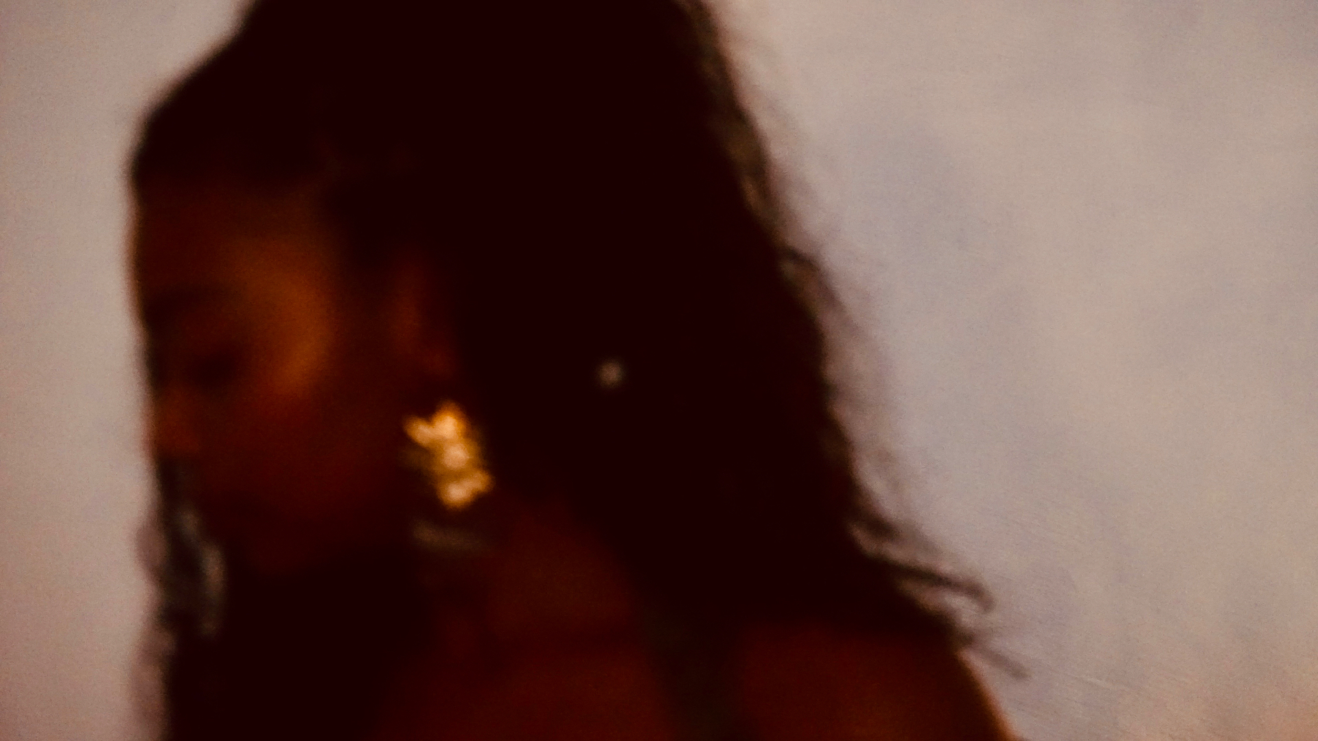 Profile of Aaniyah in warm amber light with a gold earring catching the lamp