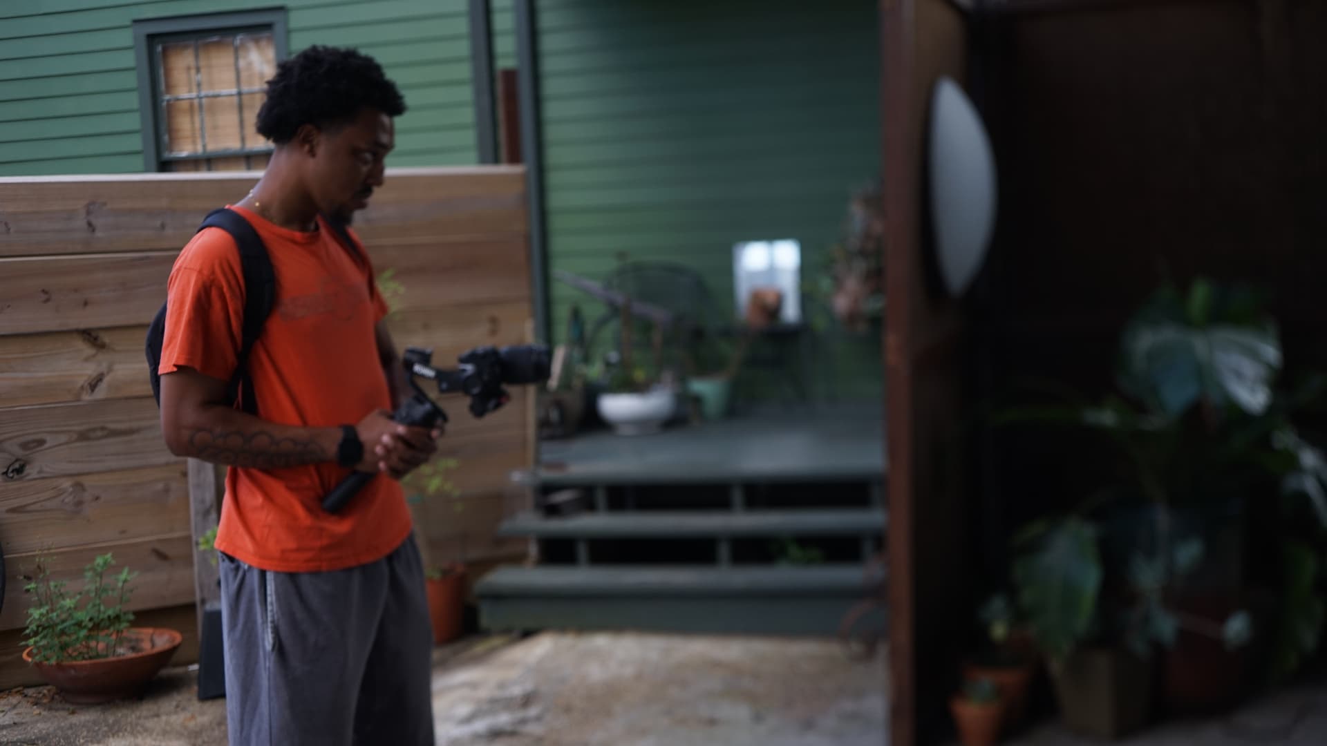 Director Mac Infinity of Forever Films Forever holding a Ronin gimbal with a mirrorless camera in a New Orleans courtyard during the Have It Your Way shoot, August 17, 2026