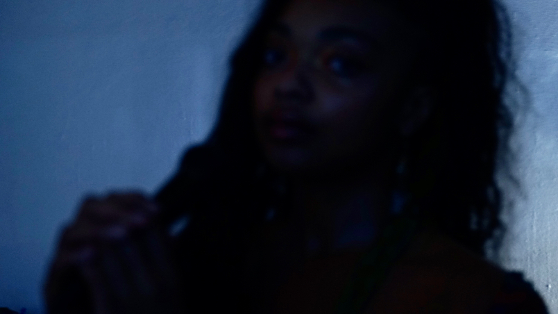 Aaniyah lit in deep blue, hand raised near her shoulder