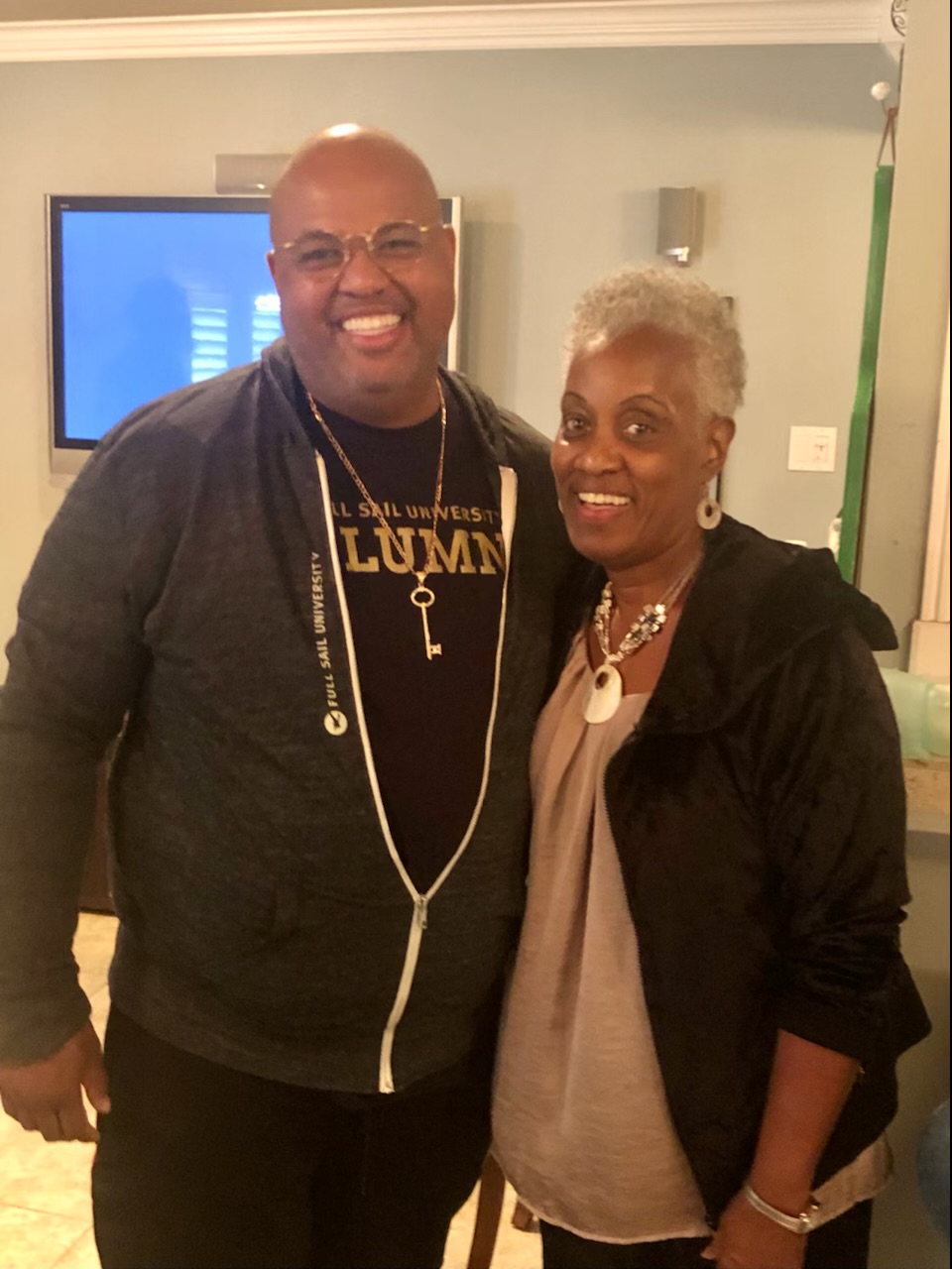 Momma Peggy smiling beside her son in a Full Sail University alumni shirt.