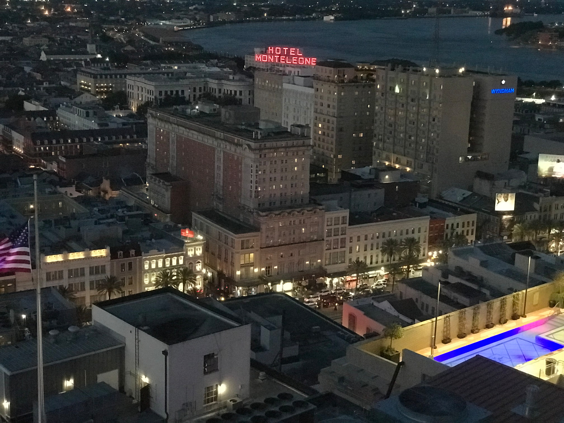 Aerial night view of the New Orleans French Quarter with the red Hotel Monteleone neon sign glowing above Royal Street and the Mississippi River beyond