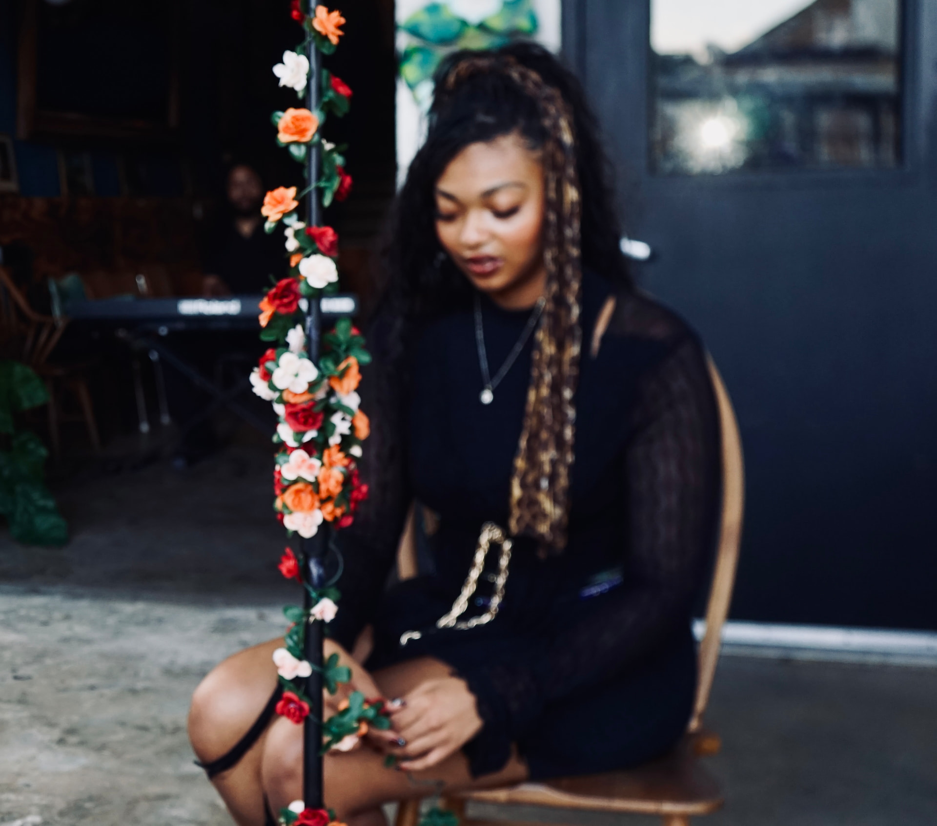 Aaniyah Anderson seated, eyes down, behind the flowered microphone stand between takes