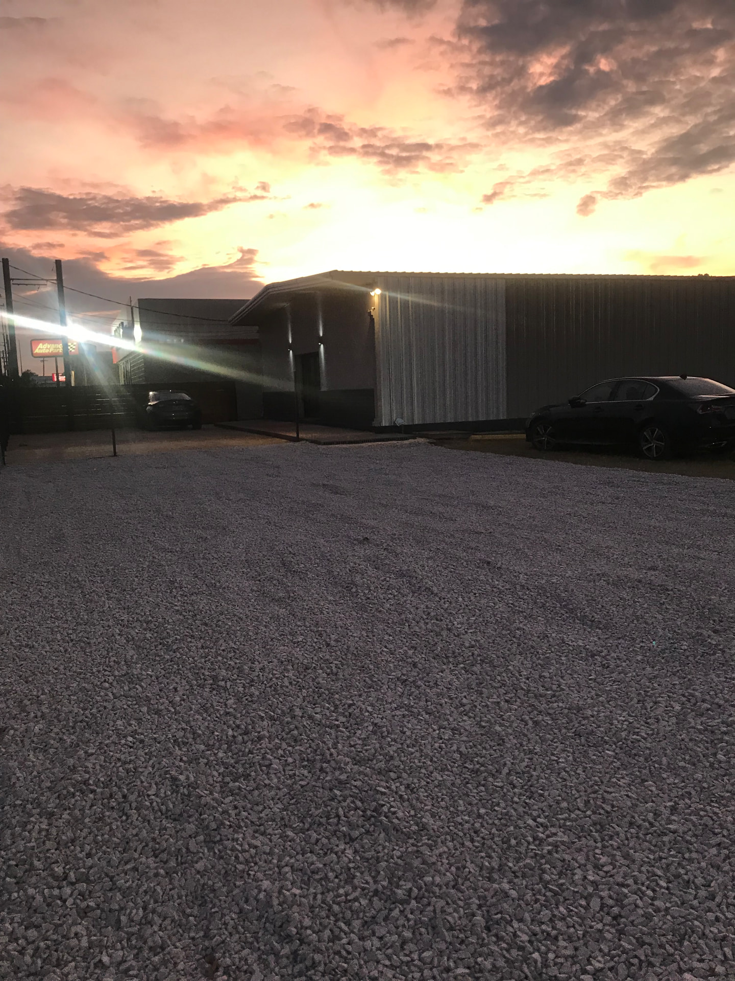 Sunset over the metal-clad exterior of The Box Studios of New Orleans with a gravel parking lot in the foreground